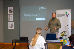 Lektors Gusts Gudelis rāda prezentāciju.