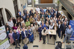 Cilvēku pūlis stāv un skatās uz augšu