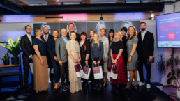 Grupas bilde uz skatuves ar visiem piču fināla dalībniekiem, pasākuma moderatoru un žūriju.