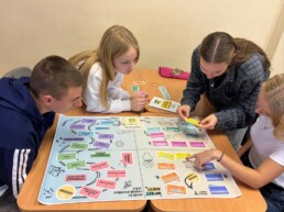 Četru skolēnu grupa spēlē galda spēli.