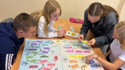 $ kids sitting around the table and playing game