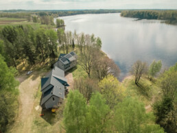 Viesu māja pie upes, mežu ieskauta no putna lidojuma.